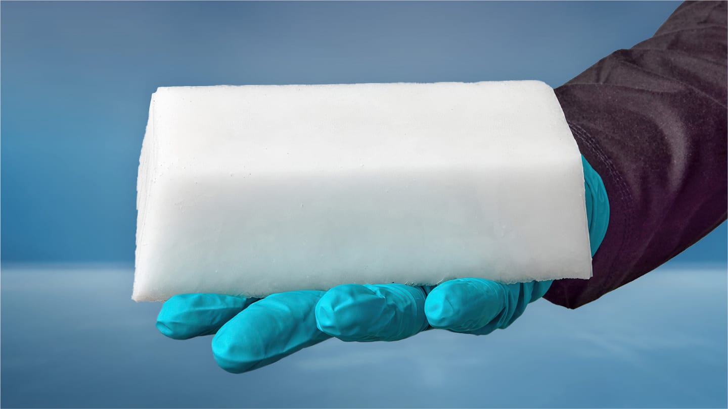 A gloved hand holding a white fuel block