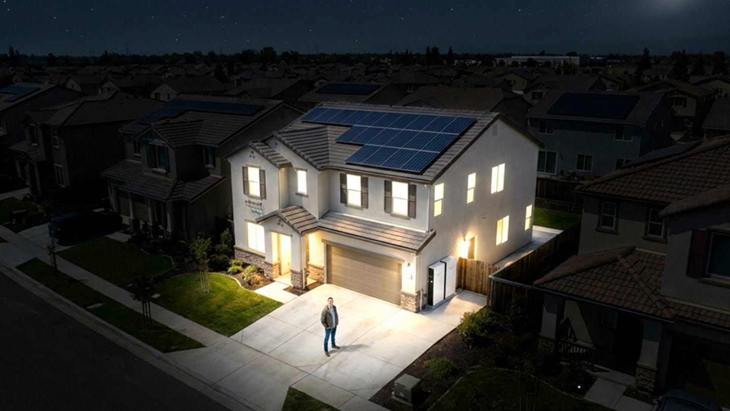 Someone stood in front of a brightly lit house