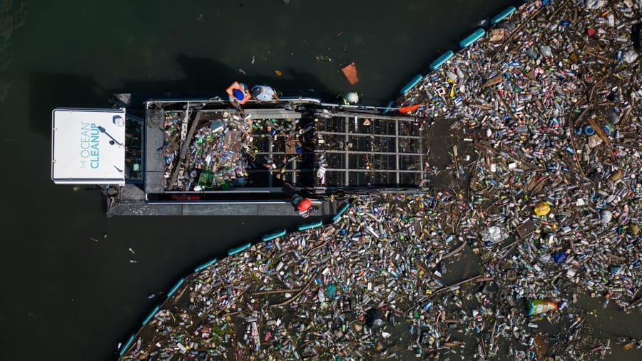 An Ocean Cleanup barge picking up waste plastic from a river